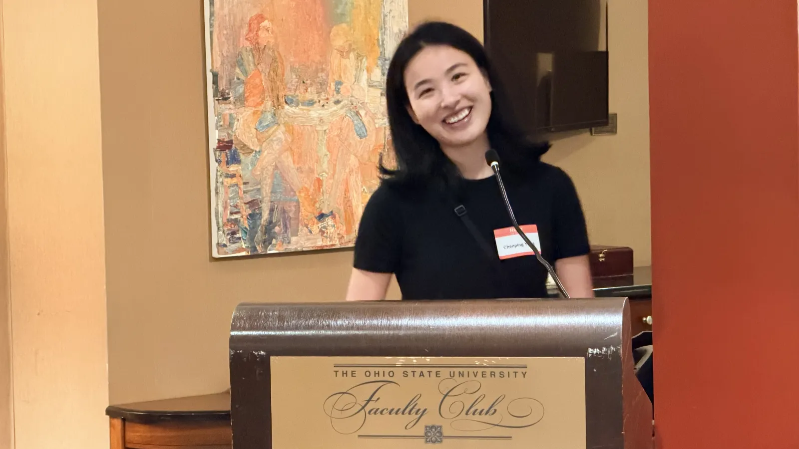 Assistant Professor Chenping Yang, smiling at the podium