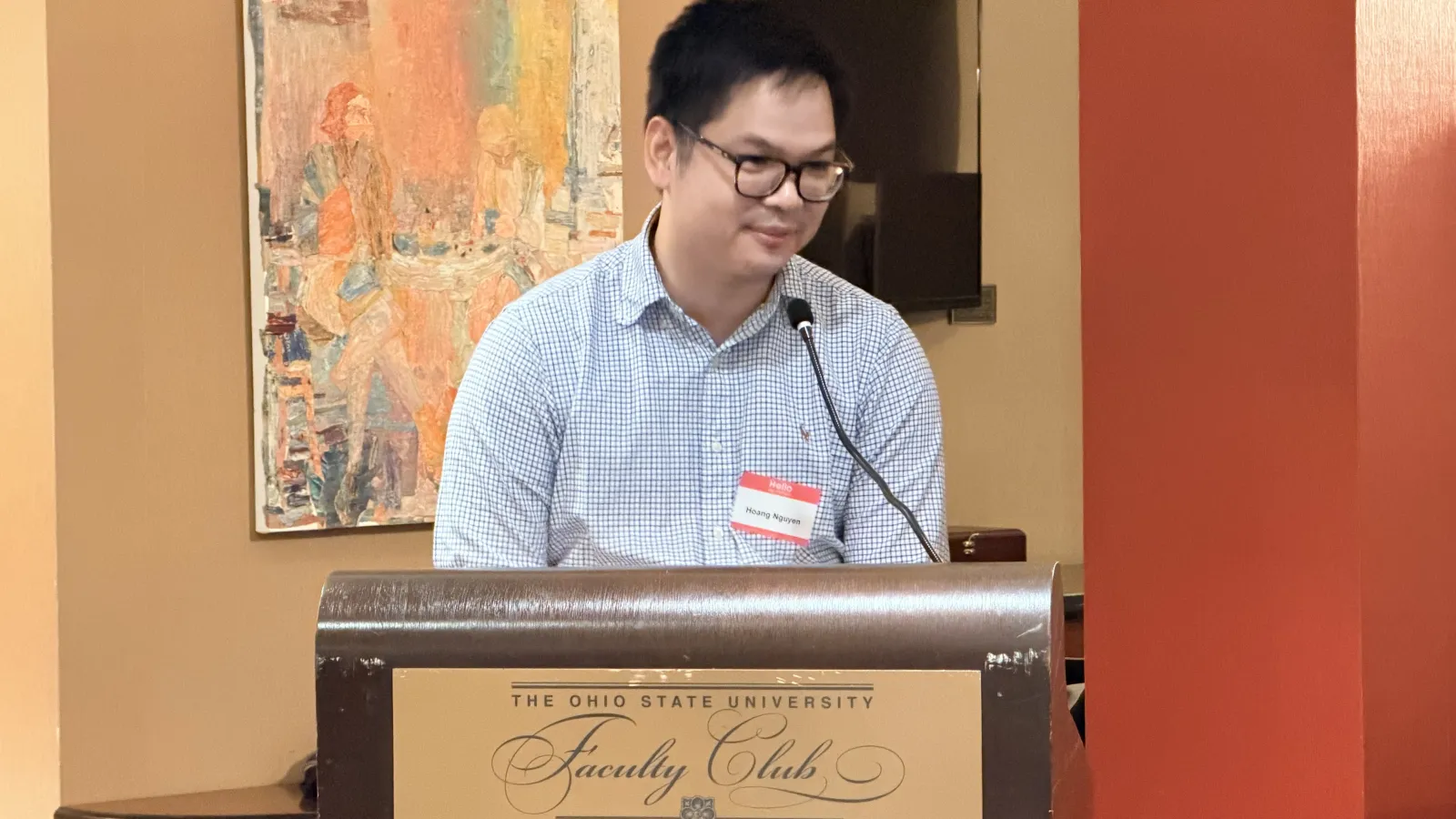 Assistant Professor Hoang Nguyen, smiling at the podium