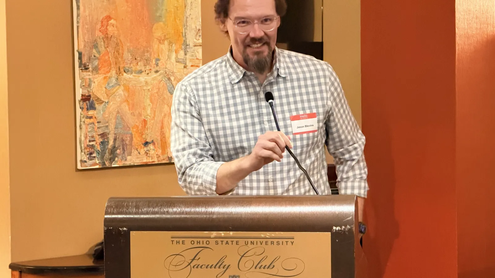 Professor Jason Blevins, smiling at the podium